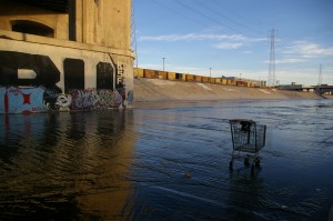Under the Sixth Street Bridge, a shopping cart sits in the Los Angeles River.